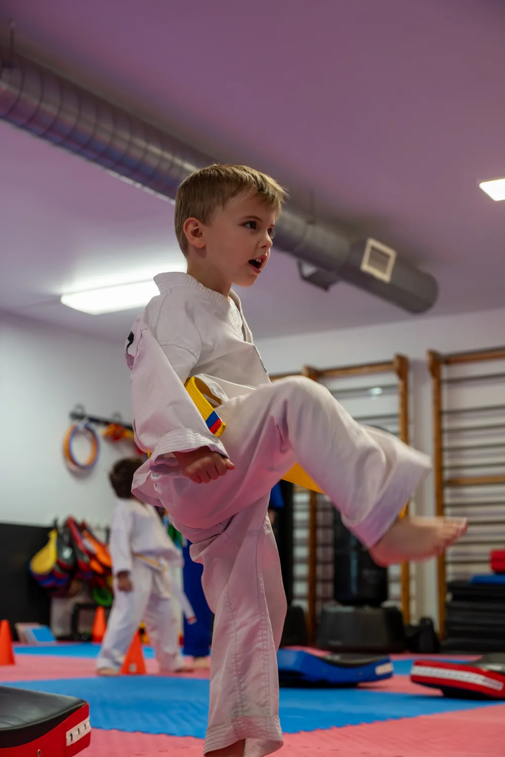 Jeune enfant en dobok effectuant un coup de pied, ceinture jaune