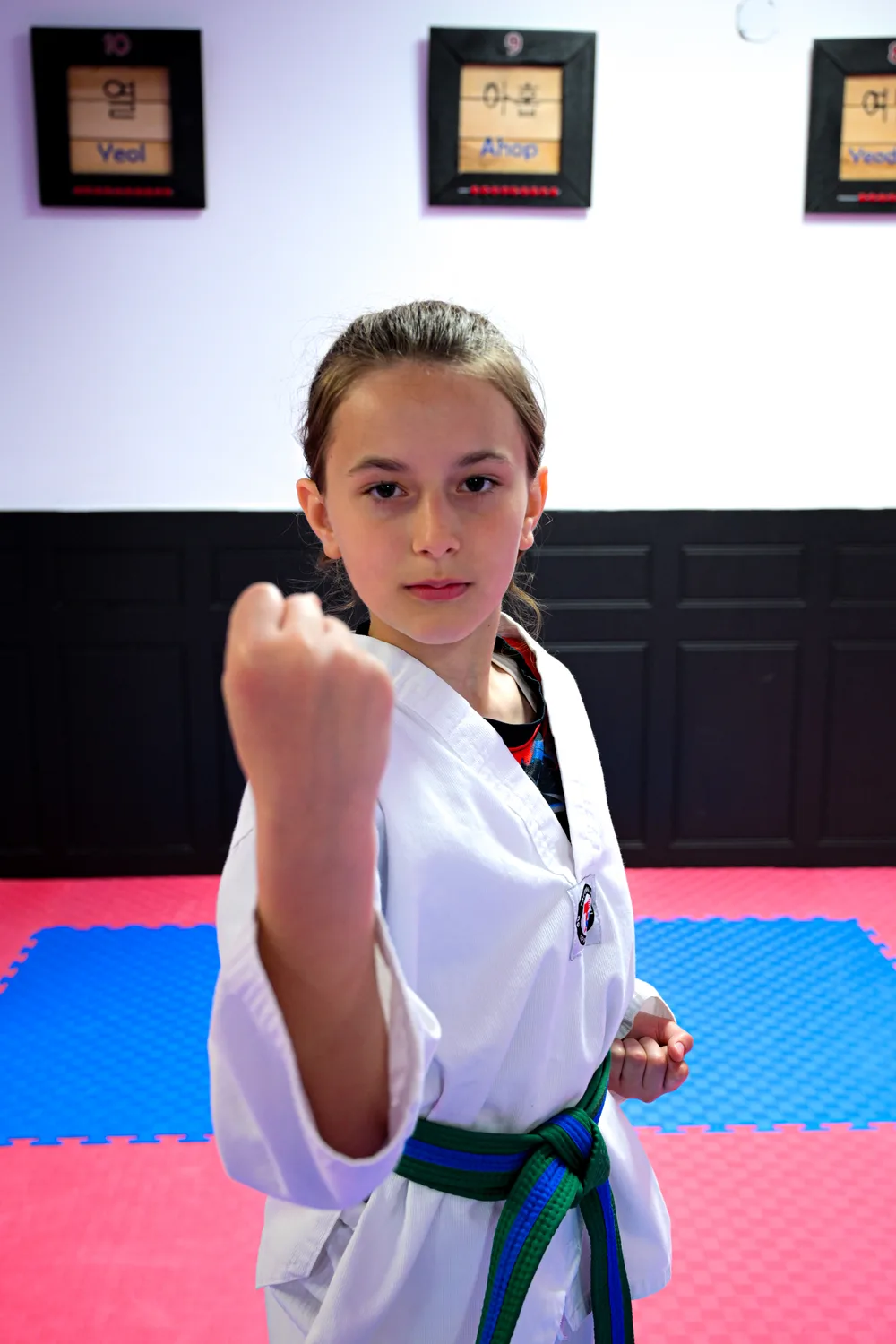 Jeune fille en position de garde, poing fermé, ceinture verte et bleue